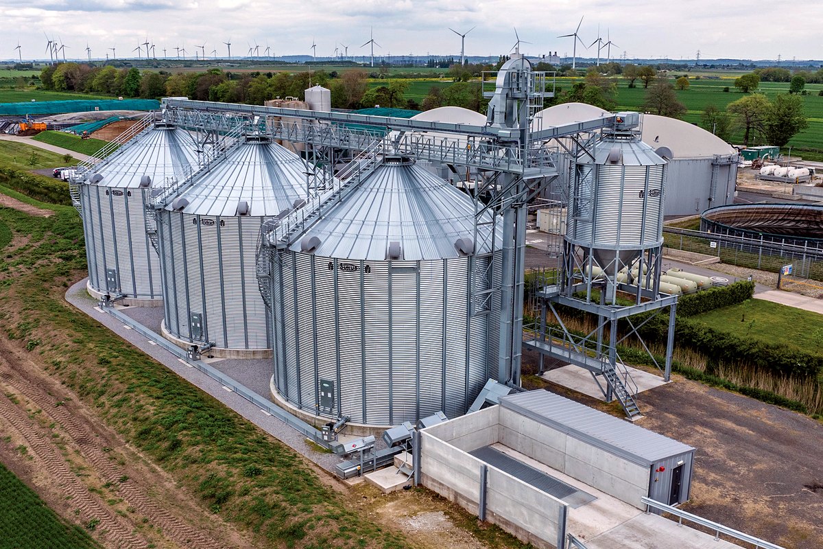 Grain storage silos on a UK farm with wind turbines beyond